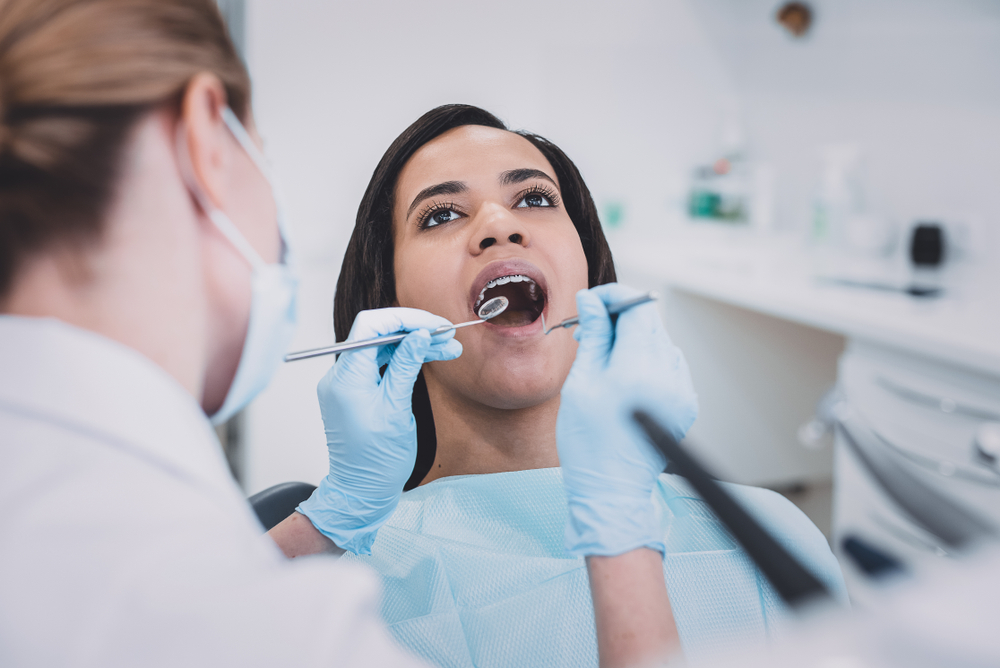 dentist examining patient's teeth with dental tools