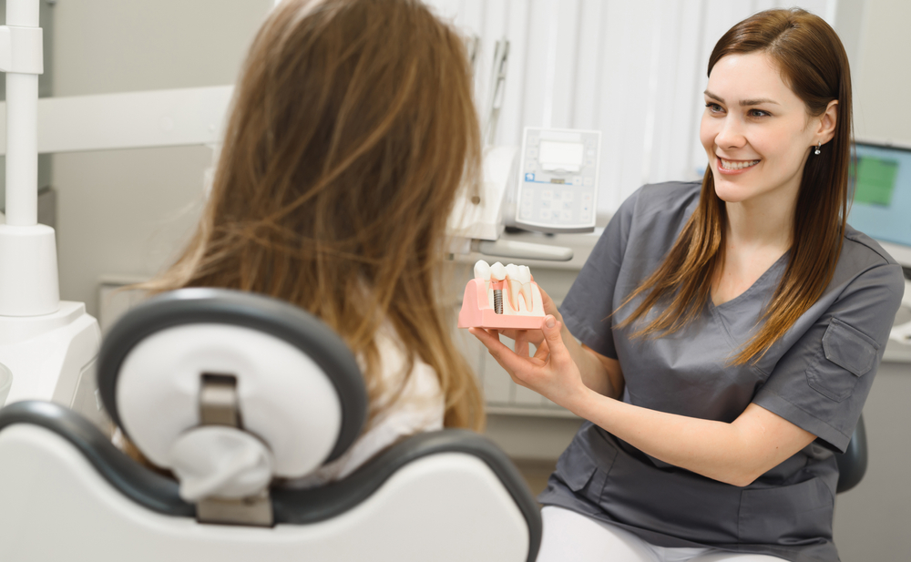 dentist showing patient model of dental implants